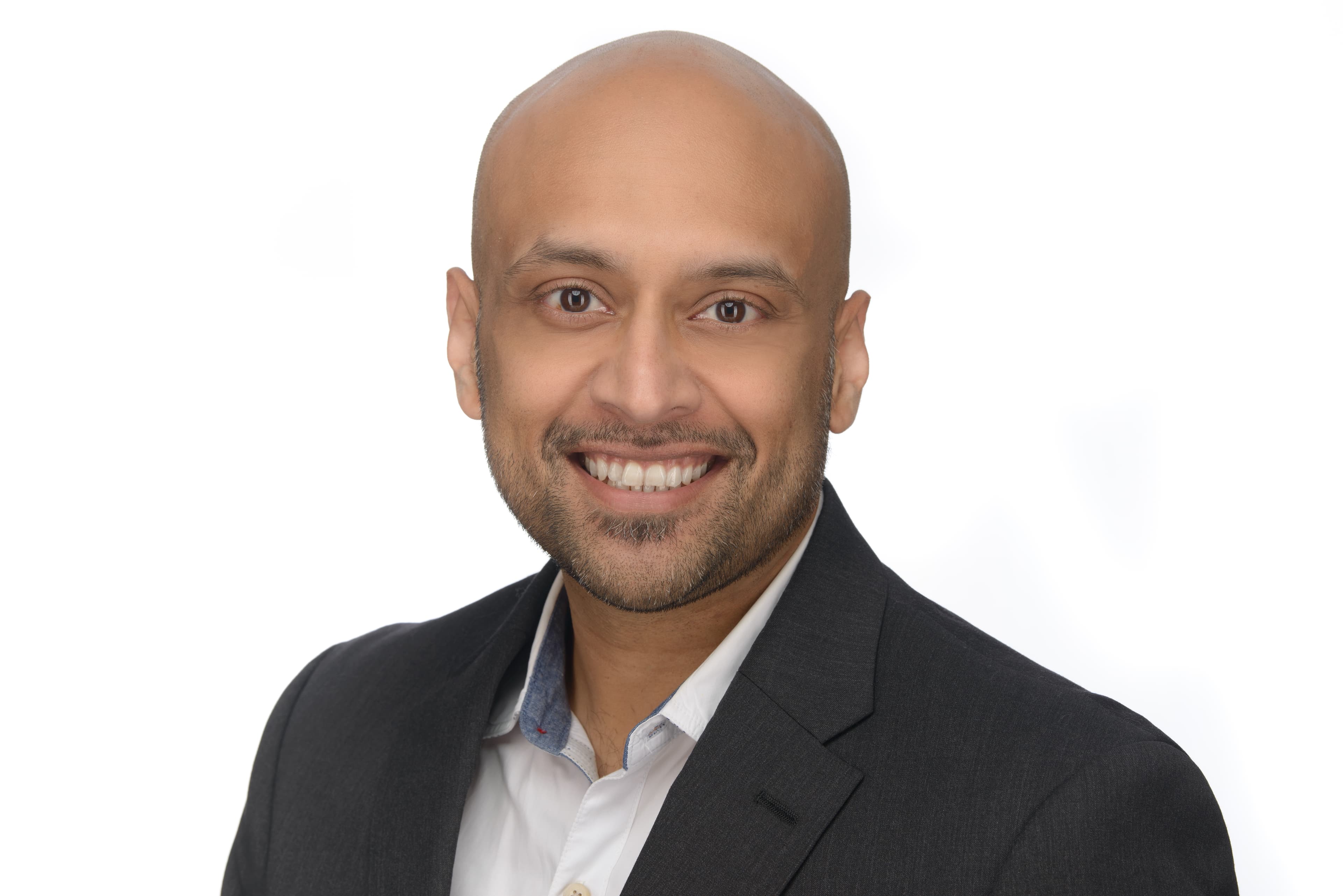 Smiling bald man with a short beard wearing a grey blazer and white shirt.